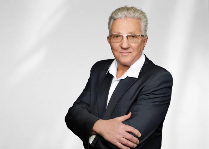 Mann im Jackett und Hemd vor grauem Hintergrund